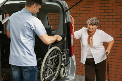 man assisting elderly woman in getting on the car